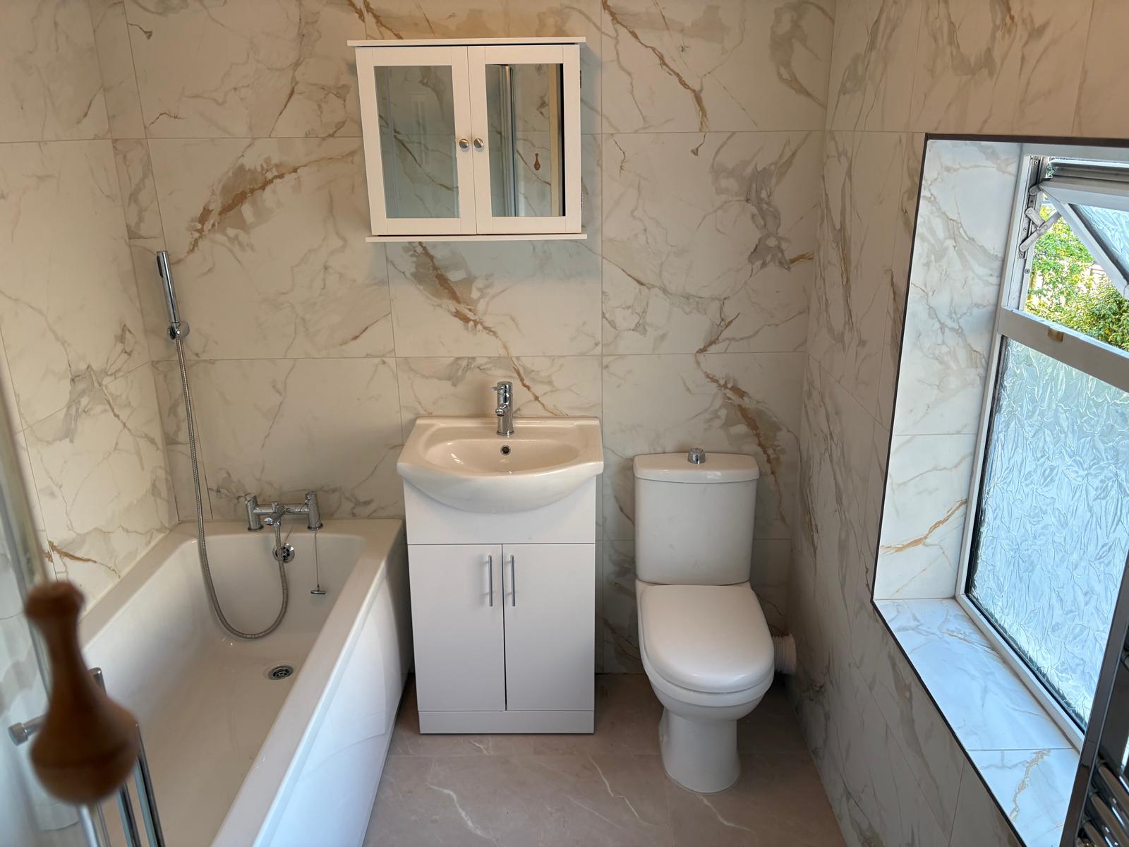 Family bathroom in calacatta gold marble-effect tiles with bath and vanity unit