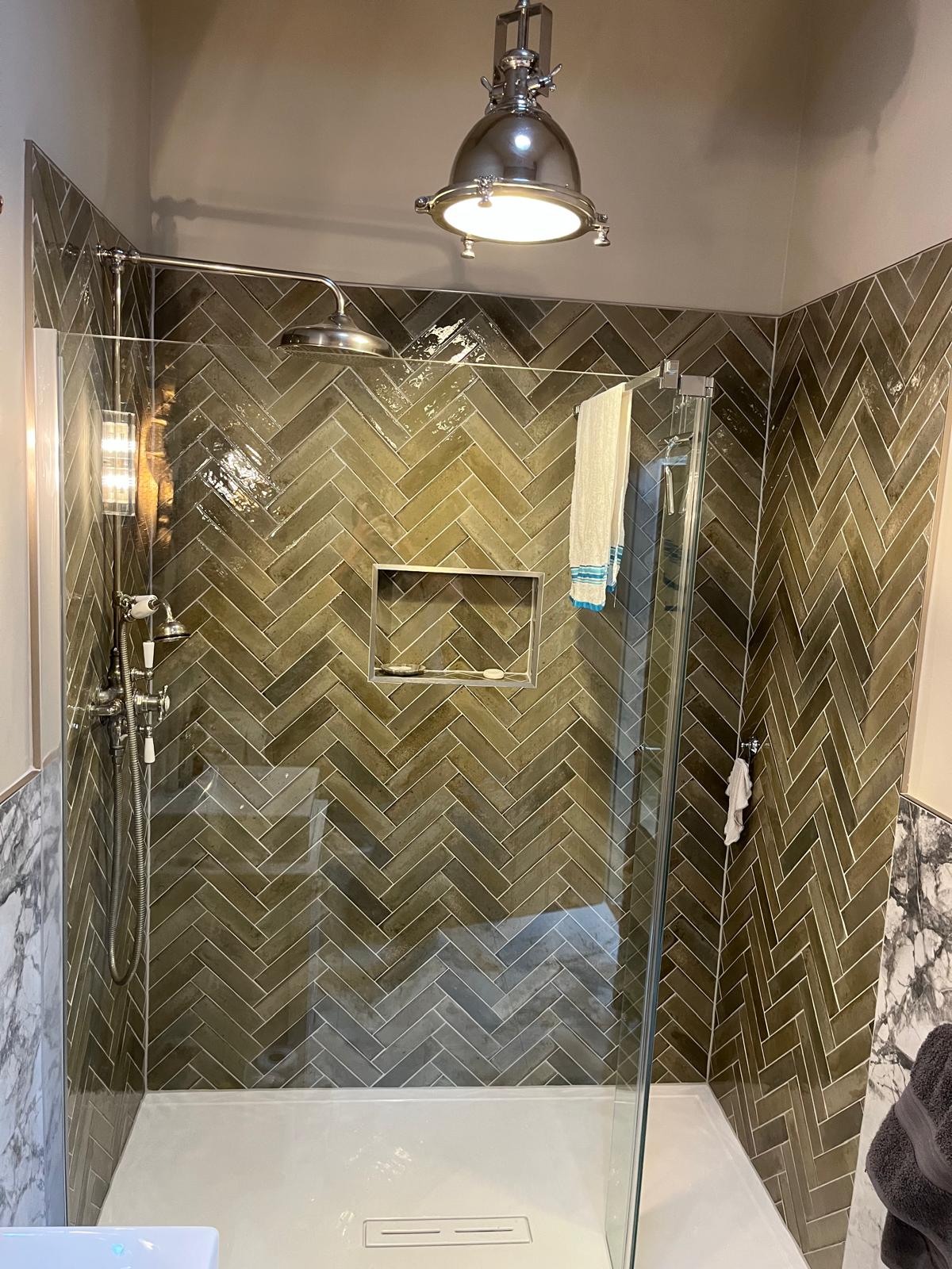 Olive green herringbone tiled shower with traditional nickel shower set and niche