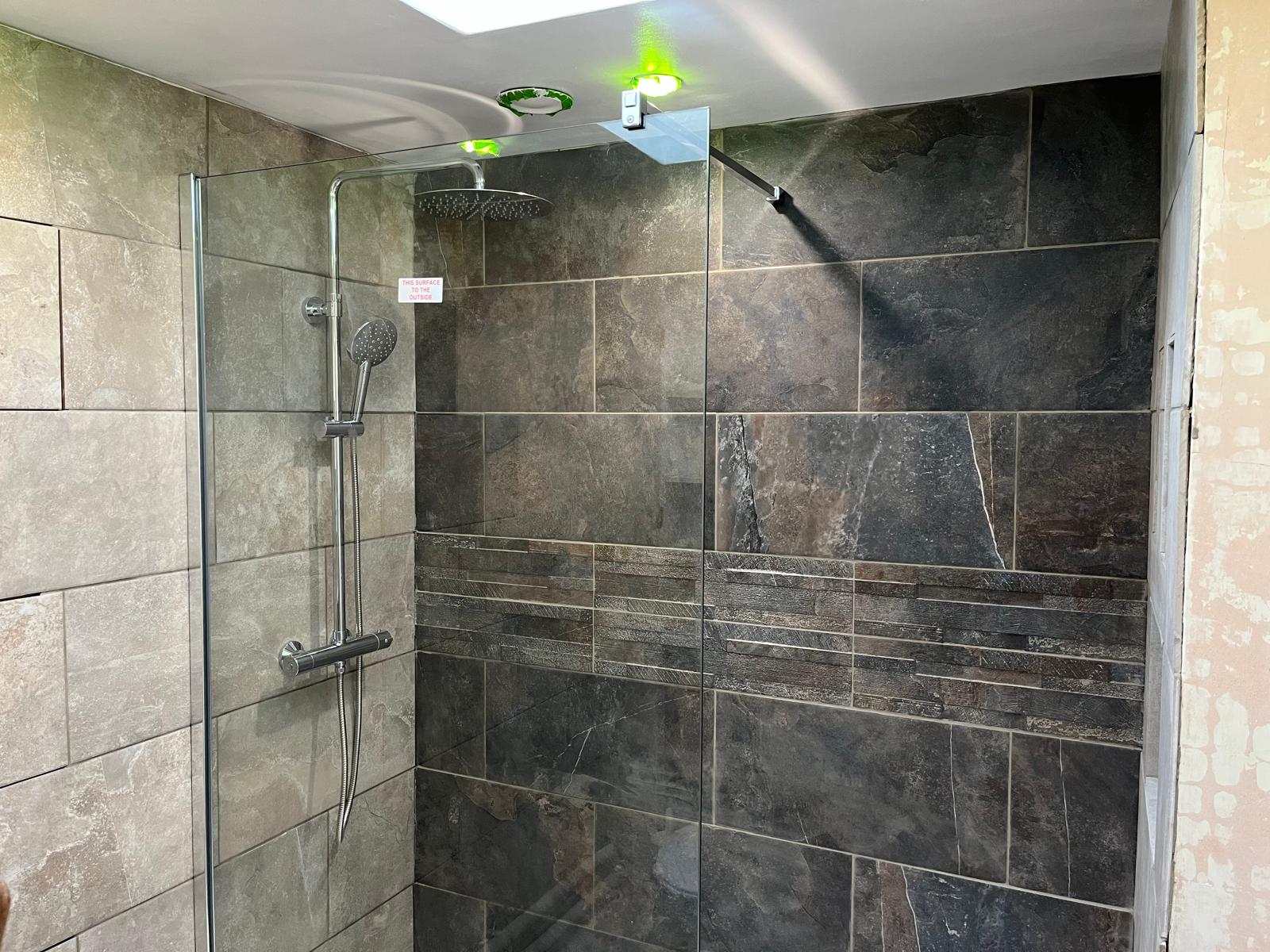Walk-in shower with dark slate tiles and split-face feature band